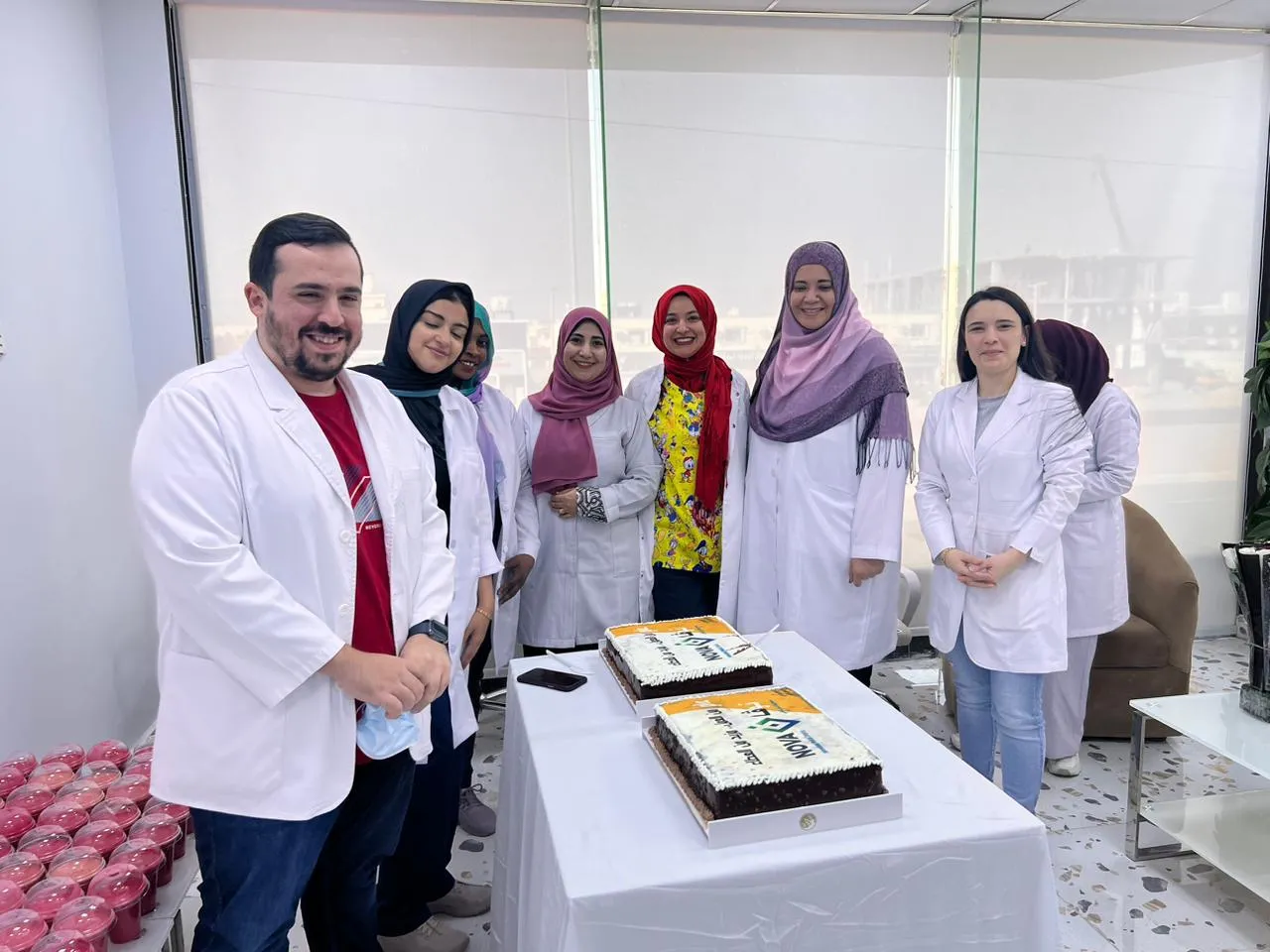 الفريق الطبي بالمعاطف البيضاء خلف كعكتي الاحتفال