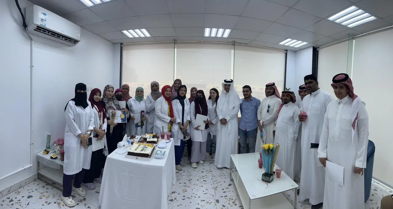 صورة جماعية للفريق الطبي والإداري في قاعة الحفل حول طاولة الكعك
