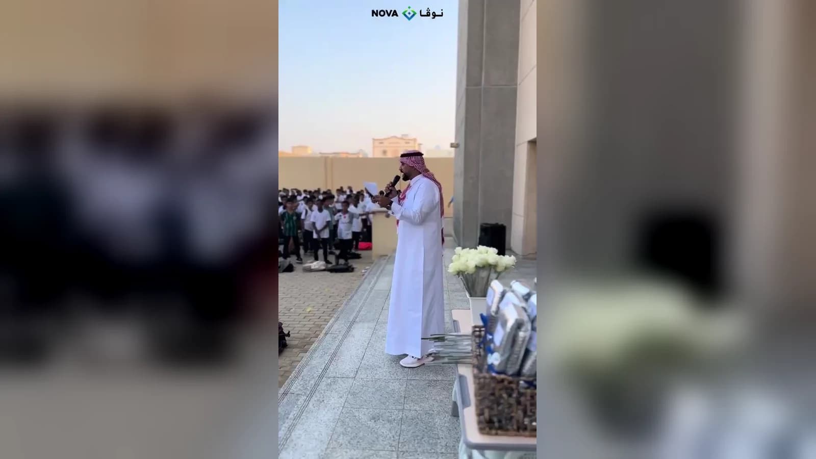 كلمة تُلقى بالميكروفون في طابور الصباح أمام طلاب المدرسة المصطفّين في ساحة المدرسة خلال زيارة فريق نوفا