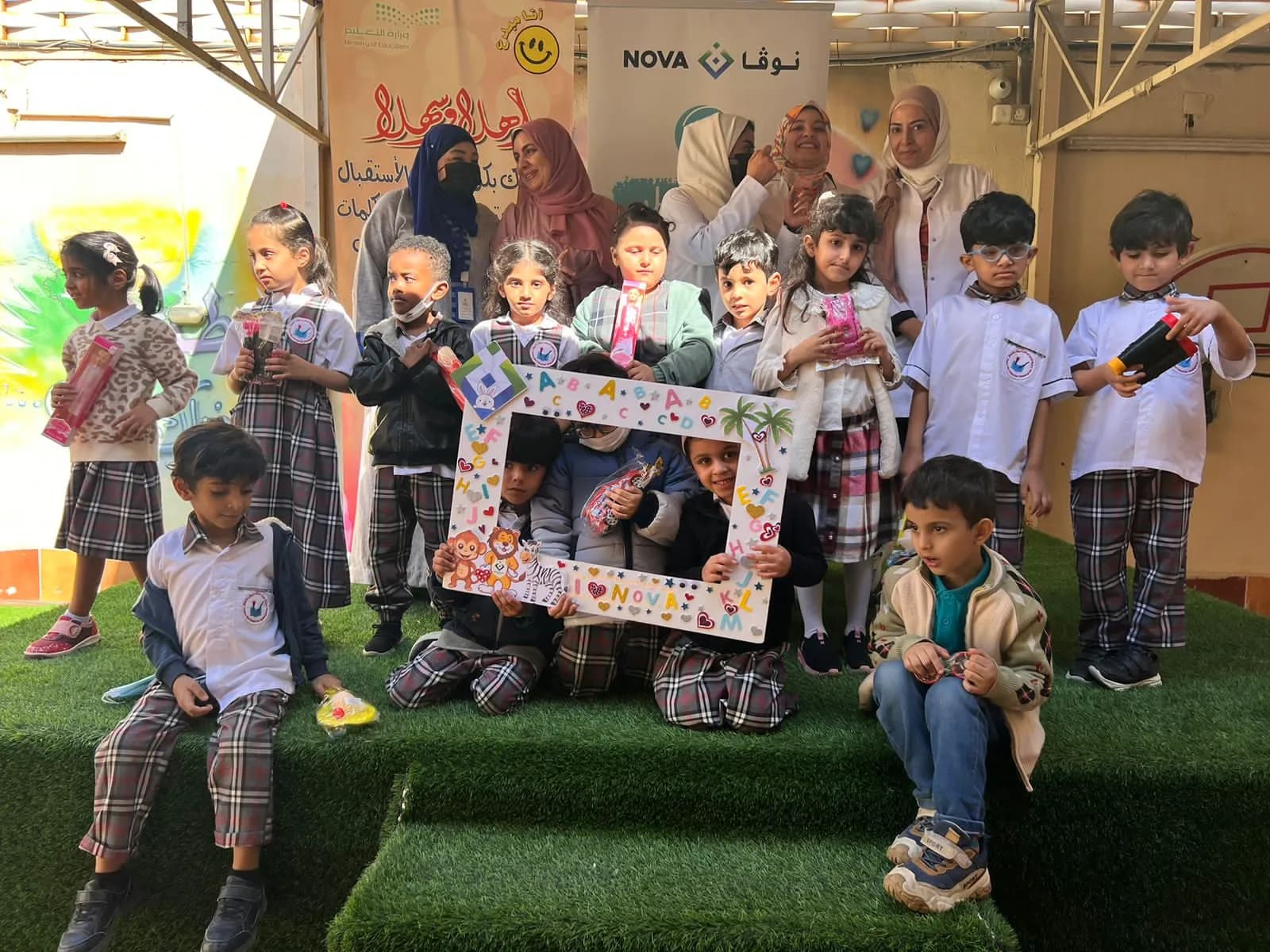 أطفال الروضة مع فريق نوفا الطبي في صورة جماعية على الملعب